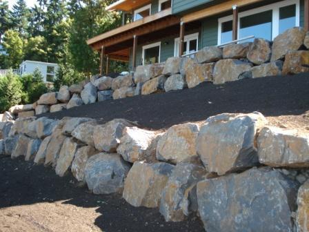 Image of a terraced retaining wall installation project in the front yard of a house.