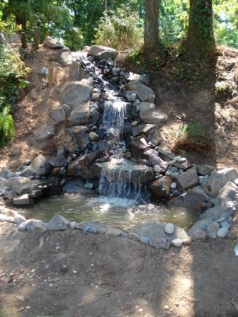 Image of cascading rock waterfall water feature system designed by Frontier Landscaping.