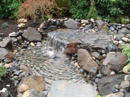 Image of a cascading rock pond and waterfall, a water feature option designed by Frontier Landscaping.